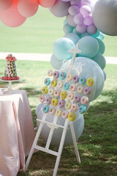 a table topped with donuts and balloons next to a cake on top of a stand