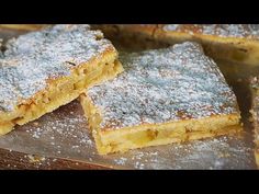 several pieces of dessert sitting on top of a cutting board covered in powdered sugar