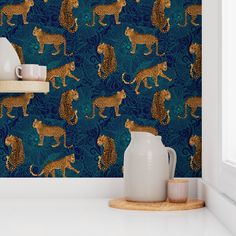 a blue wall with gold cheetah and leopards on it, next to a white vase