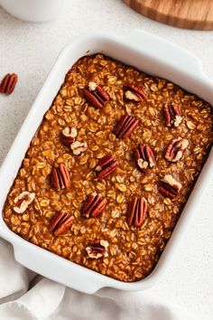 a casserole dish filled with oatmeal and pecans on a table