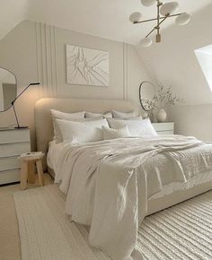 a white bed sitting under a window next to a dresser and lamp in a bedroom