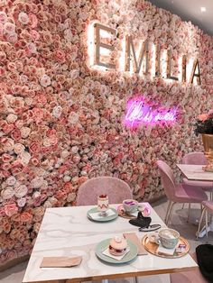 a restaurant with pink flowers on the wall and tables set up in front of it