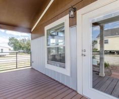 the front porch has two doors and is next to an open door that leads to a large deck