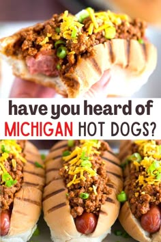 hot dogs with chili and mustard on them are being held up by someone's hand