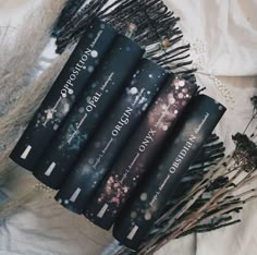 four books sitting on top of each other next to some dried flowers and twigs in front of them