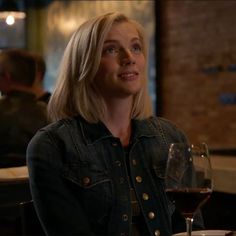 a woman sitting at a table with a glass of red wine in front of her