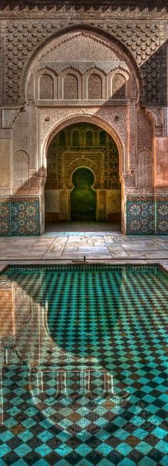 the inside of an ornate building with a pool in front of it and tiled flooring