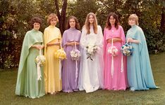 a group of women standing next to each other wearing dresses and holding bouquets in their hands