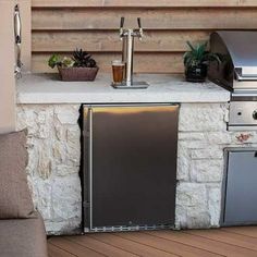 an outdoor kitchen with grill, sink and refrigerator