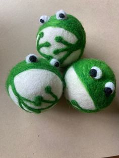 three green and white stuffed animals sitting on top of a table next to each other