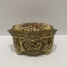 an ornately decorated gold box sits on a white surface with a floral design in the middle