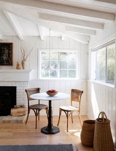 a white table and two chairs in a room with wood flooring on the walls