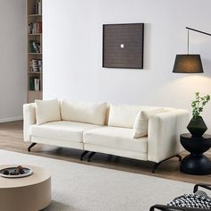 a living room filled with furniture and a white rug on top of a hard wood floor