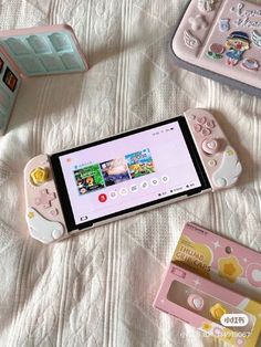 a pink nintendo wii game controller sitting on top of a bed next to other toys