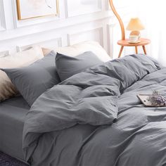 an unmade bed with grey sheets and pillows