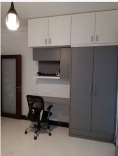 an office with white cupboards and black chair in the corner, next to a gray cabinet