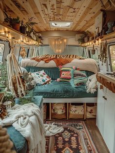 the interior of a camper van with lots of pillows and blankets on the bed