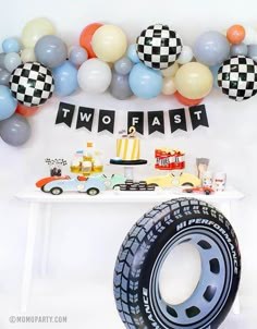 a table topped with balloons and decorations next to a race car themed dessert bar area