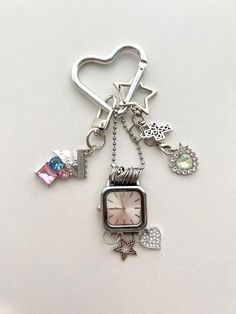 a heart shaped keychain with charms attached to it's sides and a clock on the front