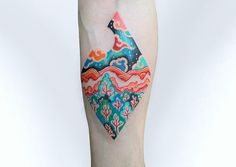 a colorful tattoo on the leg of a woman's right arm with an abstract design