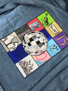 a patch on the back of a jean jacket that has various stickers on it