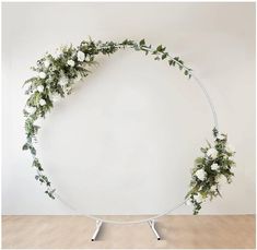 a white circle with flowers and greenery on it in front of a white wall