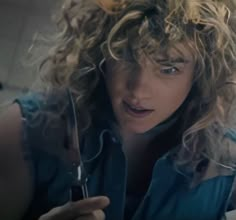 a woman with curly hair holding a knife and fork