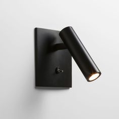 a black wall light mounted on the side of a white wall