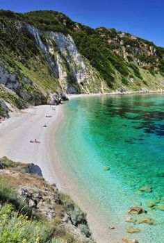 a beach with clear blue water surrounded by mountains