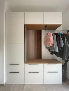 an open closet with clothes hanging on the wall and coat racks in front of it