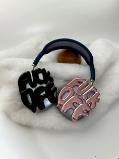 two black and pink bracelets with the word boo on them sitting on a white fur covered surface