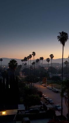 the sun is setting behind palm trees in this view from an apartment balcony at dusk