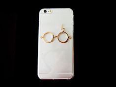 an iphone case with some glasses attached to the back of it, on a black background