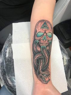 a person with a tattoo on their arm that has a skull and snake on it