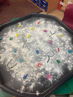 a black tray with letters and numbers on it in the middle of a playroom