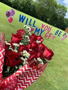 a bouquet of red roses sitting on top of a grass covered field