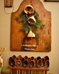 a wooden sign with bells hanging from it's side and christmas decorations on the wall