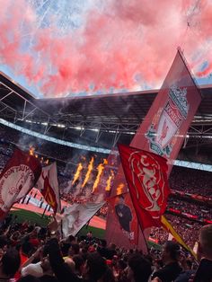 a stadium filled with lots of people holding flags and fireworks in the sky above them