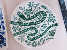 two plates with designs on them sitting next to each other, one has a snake