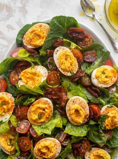 a salad with hard boiled eggs, bacon and lettuce in it on a white plate