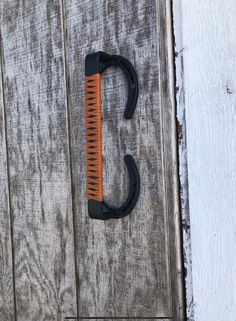 an orange and black hair comb sitting on top of a wooden floor next to a door