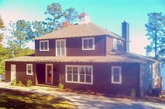 a large brown house sitting on the side of a road next to a body of water