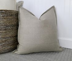 two pillows sitting next to each other on top of a bed in front of a basket