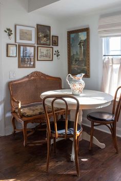 a dining room table and chairs with pictures on the wall