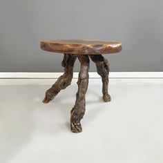 a small wooden table sitting on top of a white floor next to a gray wall