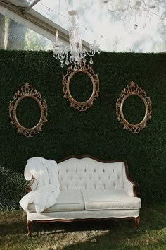 a couch sitting in front of a green wall with two mirrors on it's side