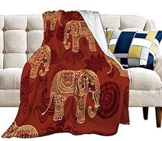 an elephant blanket sitting on top of a couch in front of a white sofa with pillows