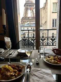 two plates of food on a table in front of the eiffel tower