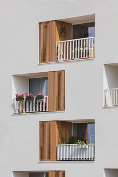 three balconies on the side of a white building with flowers in each window