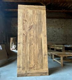 a large wooden door sitting in the middle of a room next to tables and benches